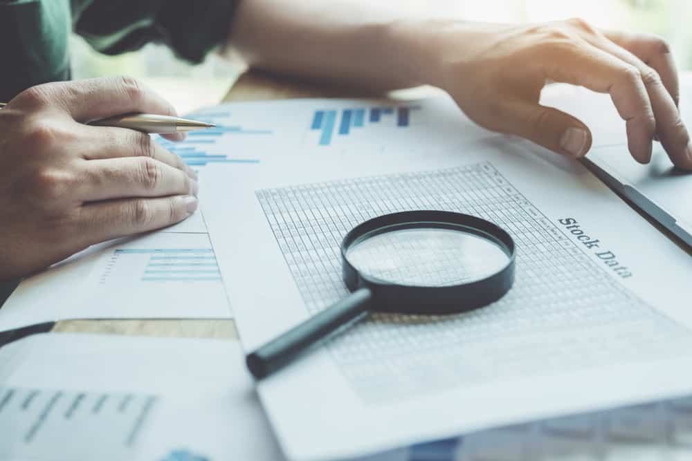 Business,Man,Using,Magnifying,To,Review,Balance,Sheet,Annual,With cdi
