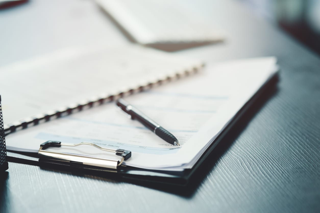 Shot of a notebook and pen on a desk in an office acdis