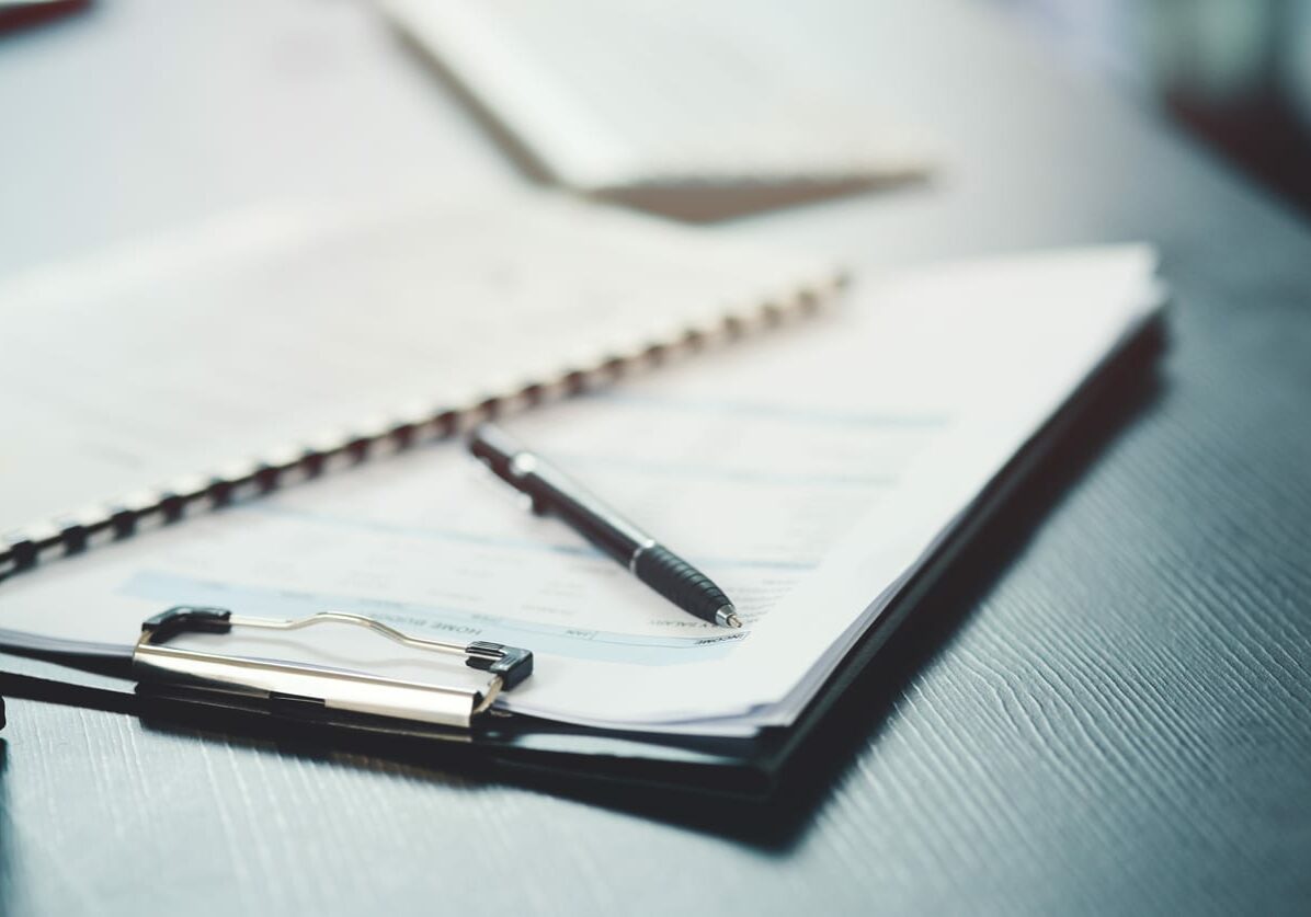 Shot of a notebook and pen on a desk in an office acdis